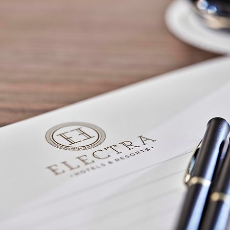 Electra Metropolis Hotel Athens Exterior photo The photo shows a letterhead or stationery featuring the logo of "Electra Hotels & Resorts." The logo includes a stylized letter "H" enclosed in a circle. There are two black pens positioned on the paper, and a glimpse of a cup, likely with coffee, i