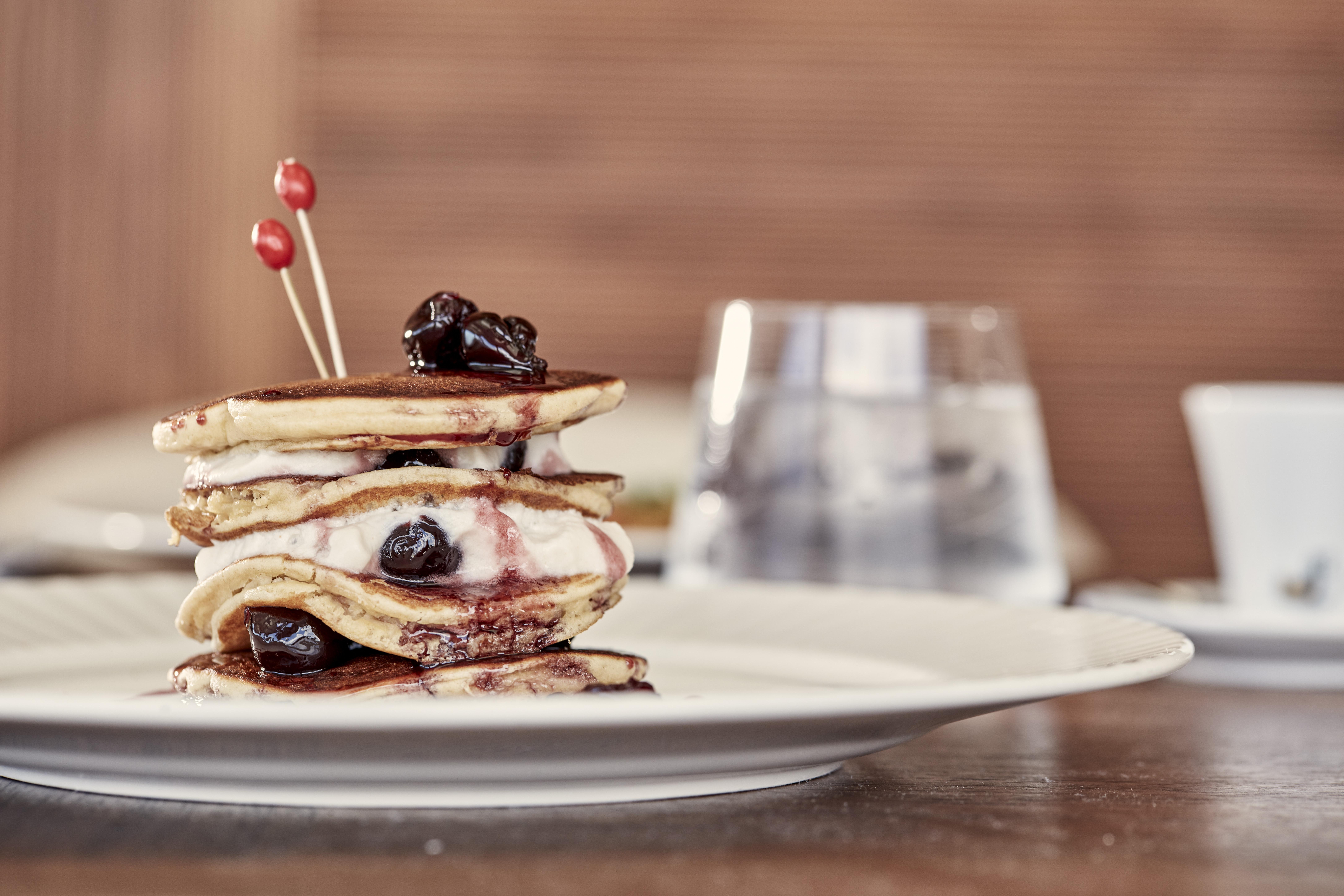 Electra Metropolis Hotel Athens Exterior photo The photo shows a stack of pancakes arranged on a plate. The pancakes are layered with a filling, possibly cream and fruit preserves or sauce, and topped with a few cherries or dark fruit. They are accented with two small red picks, giving it a decor