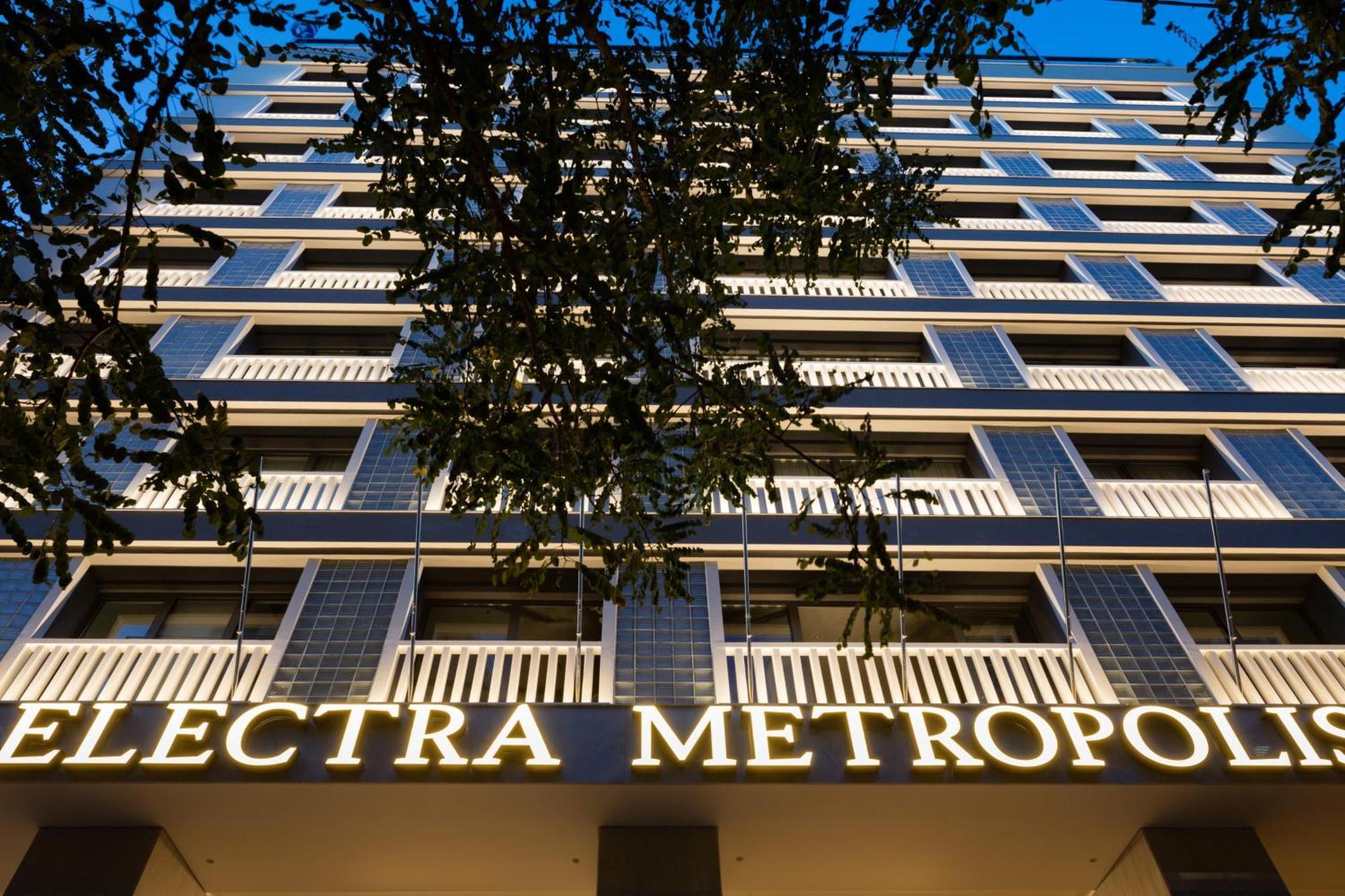 Electra Metropolis Hotel Athens Exterior photo The photo shows the facade of a building called "Electra Metropol." It appears to be a modern multi-story structure with balconies and large windows. The prominent sign with the name of the building is illuminated, making it stand out against the eve